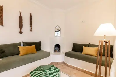 a living room with two green couches and a fireplace at Riad BAB 19 in Marrakech
