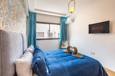 a bedroom with a bed with blue sheets and a window at Gueliz Harmony - Salon et Suites Marrakech in Marrakech