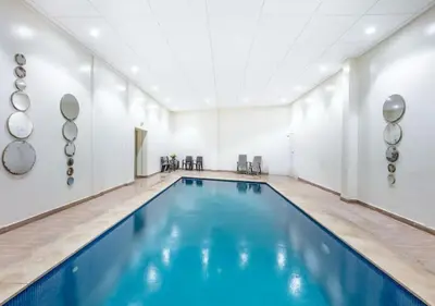 an indoor swimming pool with blue water in a room at Gueliz Harmony - Salon et Suites Marrakech in Marrakech