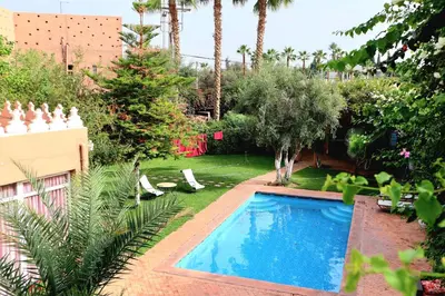 a swimming pool in a yard with palm trees at Gîte AYA in Marrakech