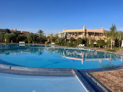 a large swimming pool with blue water in a resort at Appartement dans la palmeraie in Marrakech