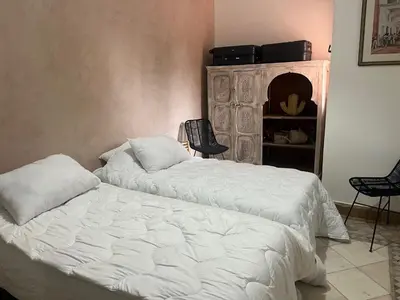 a bedroom with two white beds and a chair at Appartement dans la palmeraie in Marrakech