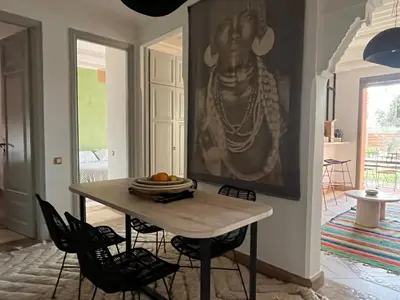a dining room with a table and a painting on the wall at Appartement dans la palmeraie in Marrakech