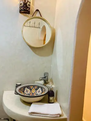 a bathroom with a sink and a mirror on a toilet at riad dar wlidati in Marrakech