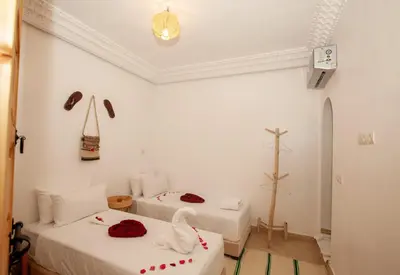 two beds in a room with a cross on the wall at riad dar wlidati in Marrakech
