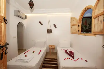 two beds in a room with white walls at riad dar wlidati in Marrakech
