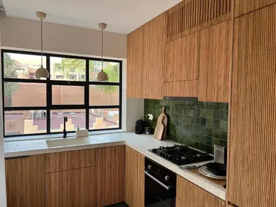 a kitchen with wooden cabinets and a stove top oven at Appartement Élégant et Spacieux Près de Carré Eden in Marrakech