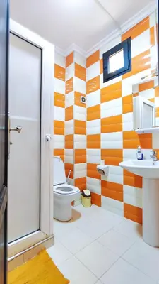 an orange and white bathroom with a toilet and sink at Bayt Al Atlas in Marrakech