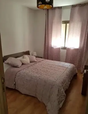 a bedroom with a bed with pink sheets and a window at Maison lala in Marrakech