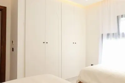 a white bedroom with white cabinets and a bed at Superbe Duplex piscine chauffée in Marrakech