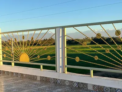 a fence with a view of a field behind it at Gîte Familial Aïcha in El Gouassem