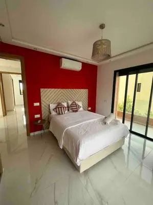 a bedroom with a large bed with a red wall at Luxueuse villa au Golf Amelkis - 5 suites in Marrakech