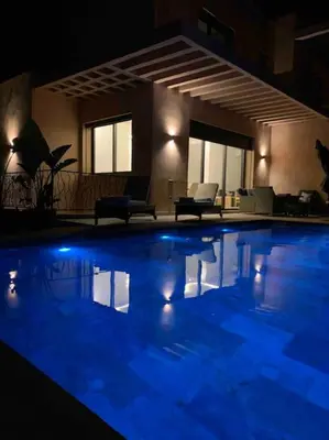 a large swimming pool at night with blue lights at Luxueuse villa au Golf Amelkis - 5 suites in Marrakech