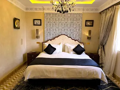 a bedroom with a large bed and a chandelier at Palais Mars in Marrakech