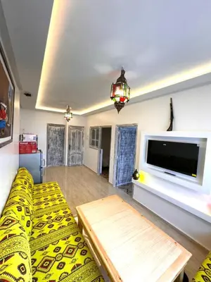 a living room with a yellow couch and a flat screen tv at cosy appartement a marrakech in Marrakech