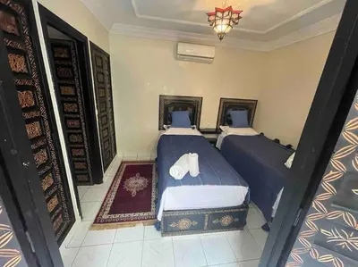 a bedroom with two beds and a chandelier at Riad mostafa in Marrakech