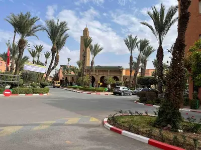 a street with palm trees and a building with a clock tower at Riad mostafa in Marrakech