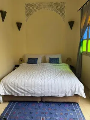a bedroom with a white bed with a blue rug at Riad Lou Kasbah in Marrakech