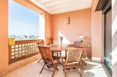 a dining room with a table and chairs on a balcony at Marrakech flat with swimming pool & sunny garden in Marrakech