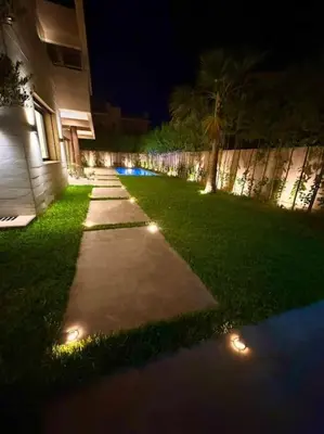 a sidewalk with lights in the grass at night at Sublime Villa avec Ascenseur Piscine chauffée in Marrakech