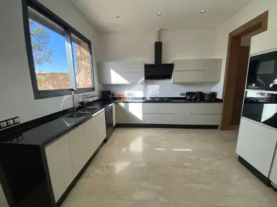 a large kitchen with white cabinets and a large window at Sublime Villa avec Ascenseur Piscine chauffée in Marrakech
