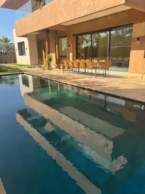 a swimming pool with chairs in front of a house at Sublime Villa avec Ascenseur Piscine chauffée in Marrakech