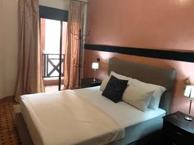 a bedroom with a white bed with two lamps and a window at Cosy Apartment with 5 pools in Marrakech
