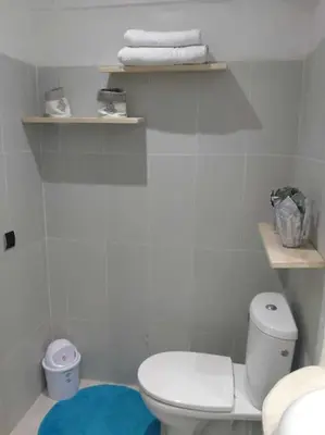 a white bathroom with a toilet and towels on shelves at Cosy Apartment with 5 pools in Marrakech