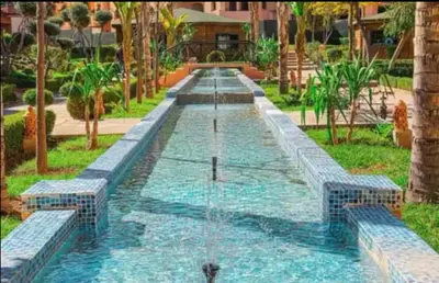 a fountain in the middle of a garden at Cosy Apartment with 5 pools in Marrakech