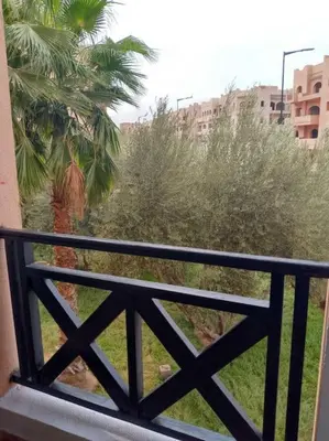 a balcony with a view of a palm tree at Cosy Apartment with 5 pools in Marrakech