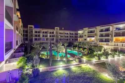 an apartment building with a pool and palm trees at night at Bonjour cher client in Marrakech