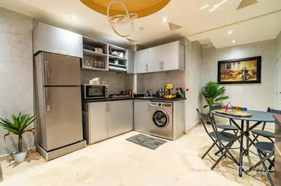 a kitchen with stainless steel appliances and a table at 5-Star Atlas Pearl well Centered in Marrakech