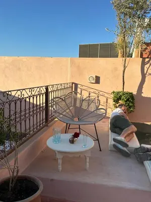 a man sitting on a balcony with a table at Le RIAD Paradis Secret in Marrakech