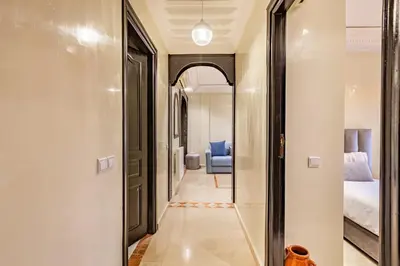 a hallway leading to a bedroom with a blue chair at Coup de coeur en plein centre ville piscine in Marrakech
