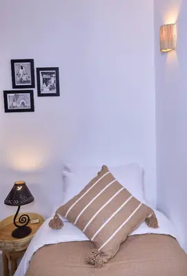 a bed with a striped pillow and a table with a lamp at Riad Tawkane in Marrakech