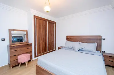 a bedroom with a bed and a dresser and a mirror at Appartement Duplex Hivernage in Marrakech