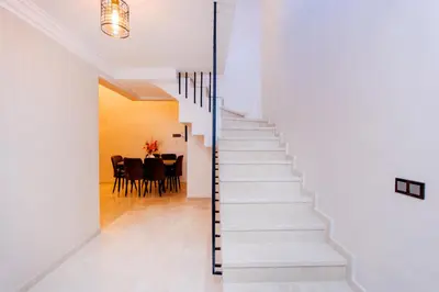 a staircase in a white house with a dining room at Appartement Duplex Hivernage in Marrakech
