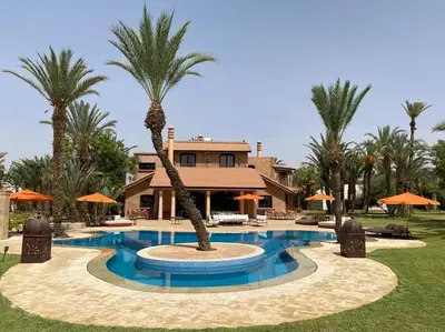 a swimming pool with a palm tree in front of a house at Villa jowehara Palmeraie Marrakech in Marrakech
