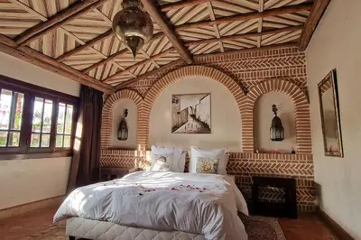 a bedroom with a large bed with a wooden ceiling at Villa jowehara Palmeraie Marrakech in Marrakech