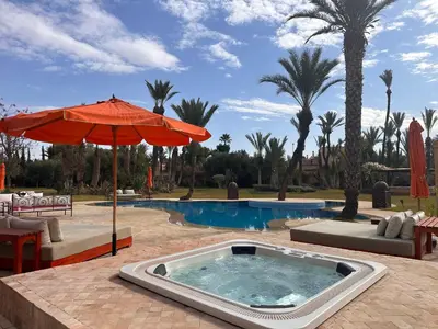 a hot tub with an umbrella next to a pool at Villa jowehara Palmeraie Marrakech in Marrakech