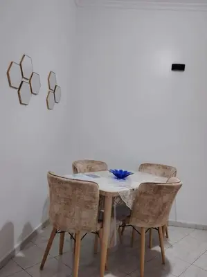 a dining room table with chairs and a white wall at Quiet and family apartment, appartement in Marrakech