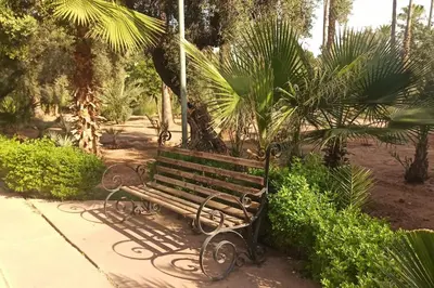 a park bench sitting on a sidewalk in a park at Charm Apt dans le triangle Tourisme de Marrakech ! in Marrakech