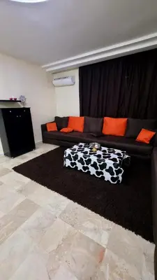a living room with a black couch with orange pillows at calme est spacieux 37 pour les familles in Marrakech