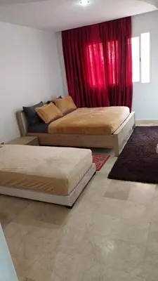 two beds in a bedroom with red curtains at calme est spacieux 37 pour les familles in Marrakech