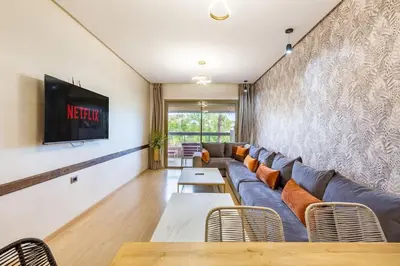 a living room with a couch and a tv at Stunning Prestigia Escape Poolside Views in Marrakech