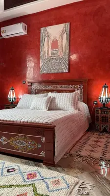 a bedroom with a bed with a red wall at Dar Yamna Maison d'Hôtes in El Gouassem