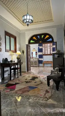 a living room with an archway and a room with a table at Dar Yamna Maison d'Hôtes in El Gouassem