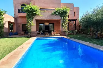 a swimming pool in front of a house at Villa avec piscine chauffée en option Palmeraie in Marrakech