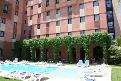 a large building with chairs and a swimming pool at Hotel Relax Marrakech in Marrakech