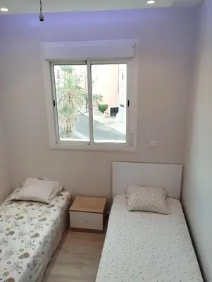 two beds in a room with a window at Appartement au centre Marrakech in Marrakech